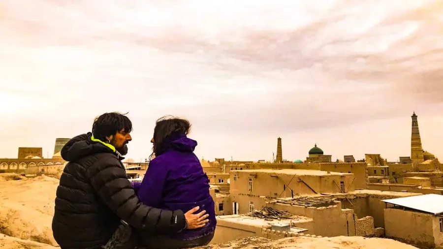 Pareja sentada de espaldas frente a una ciudad histórica de adobe