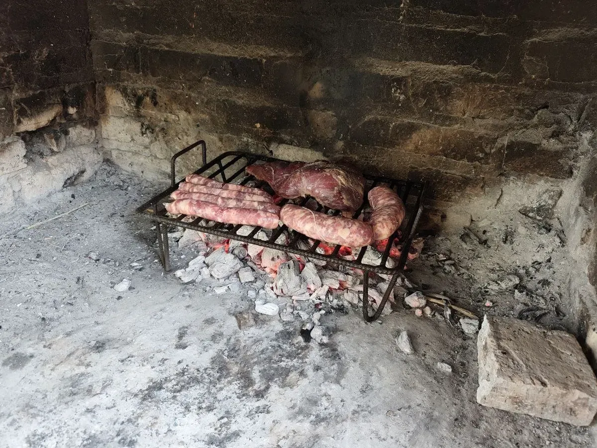 Carne y chorizos a la parrilla sobre las brasas del asador de la parcela