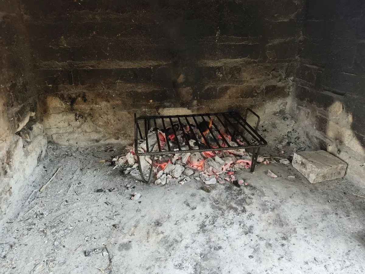 Brasas encendidas bajo la parrilla en el asador de ladrillo de la parcela