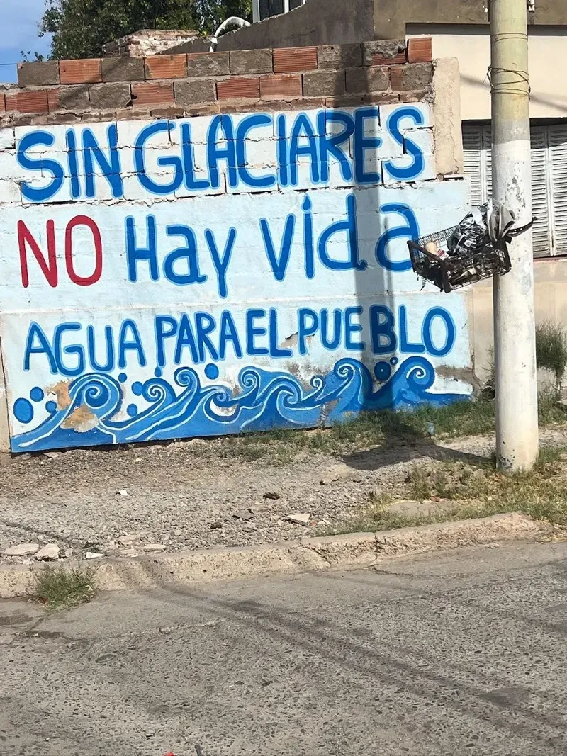 Mural pintado en una pared con el texto «Sin glaciares no hay vida. Agua para el pueblo» y olas azules
