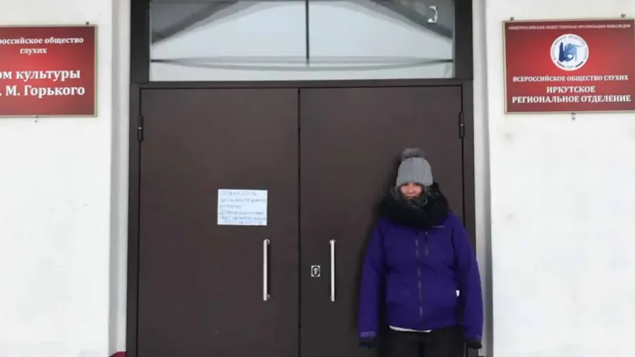 Persona abrigada frente a la puerta cerrada de un centro cultural de personas sordas en Irkutsk