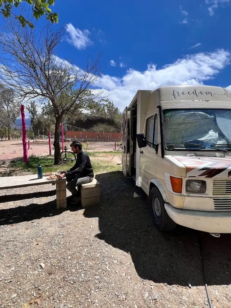 Nuestra camper aparcada junto a la oficina de turismo de Famatina, con Sergi comiendo en una mesa de cemento