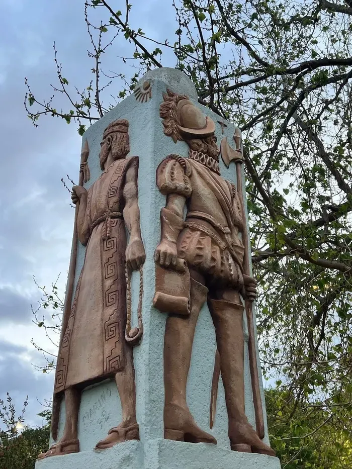 Monumento con un indígena y un conquistador español de espaldas, en relieve