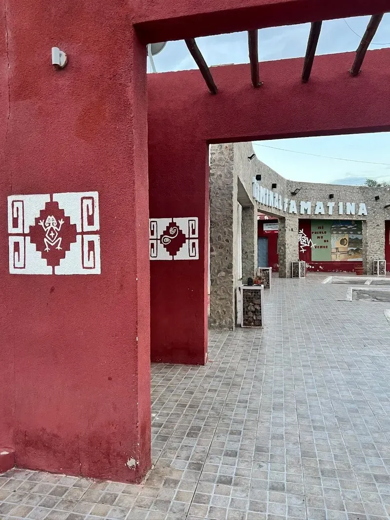 Entrada de la terminal de Famatina con pilares rojos y motivos precolombinos pintados en blanco