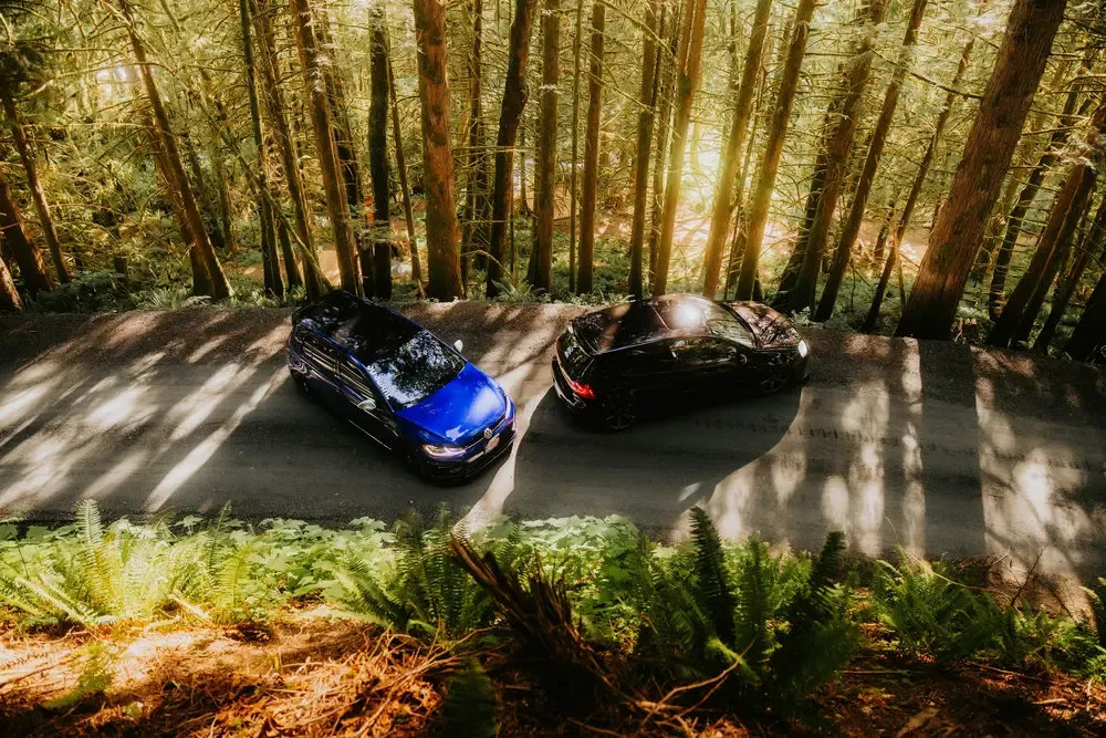 dos coches de alquiler enfrentados en carretera representando comparativa entre plataformas de alquiler de coches