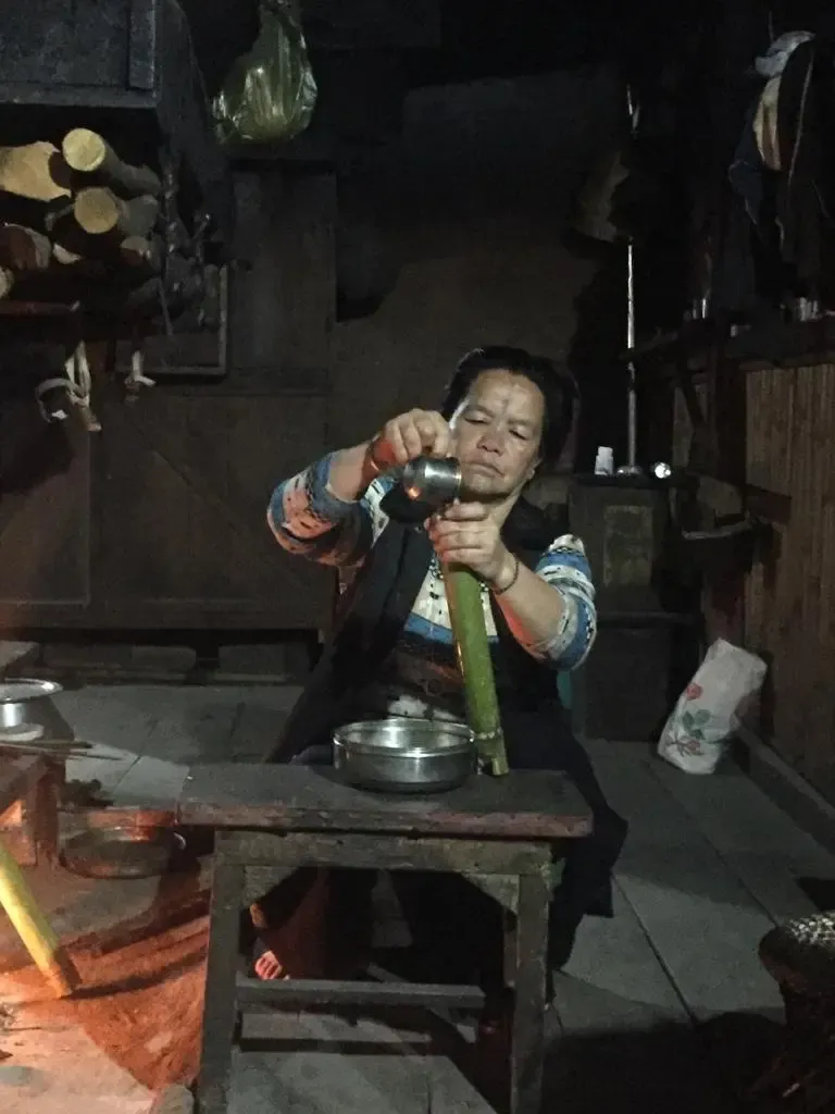Mujer de nuestro alojamiento preparando carne asada en bambú tradicional