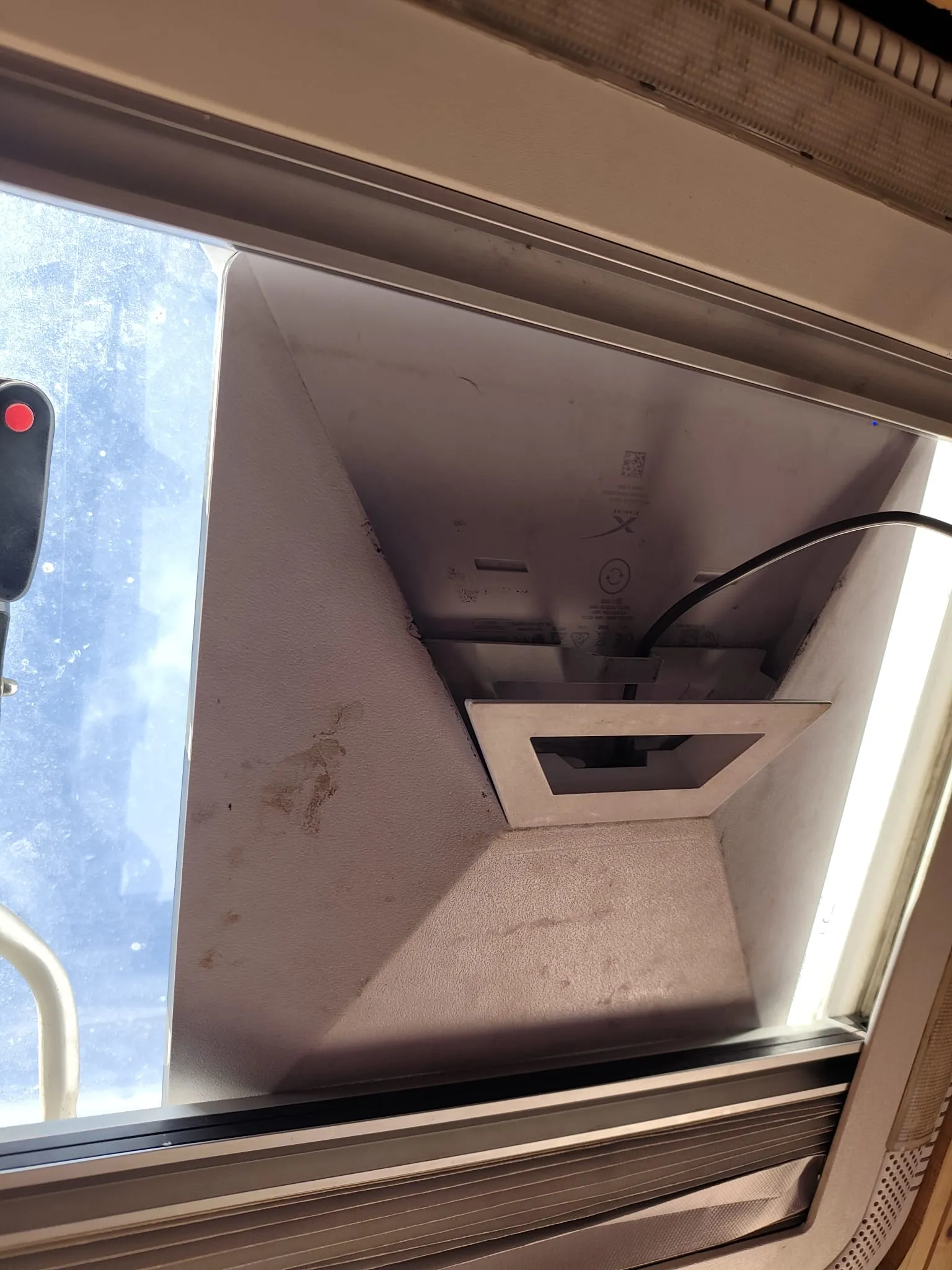 Antena Starlink Mini colocada sobre el marco abierto de la claraboya de nuestra camper, vista desde dentro, con el cable negro saliendo hacia el interior