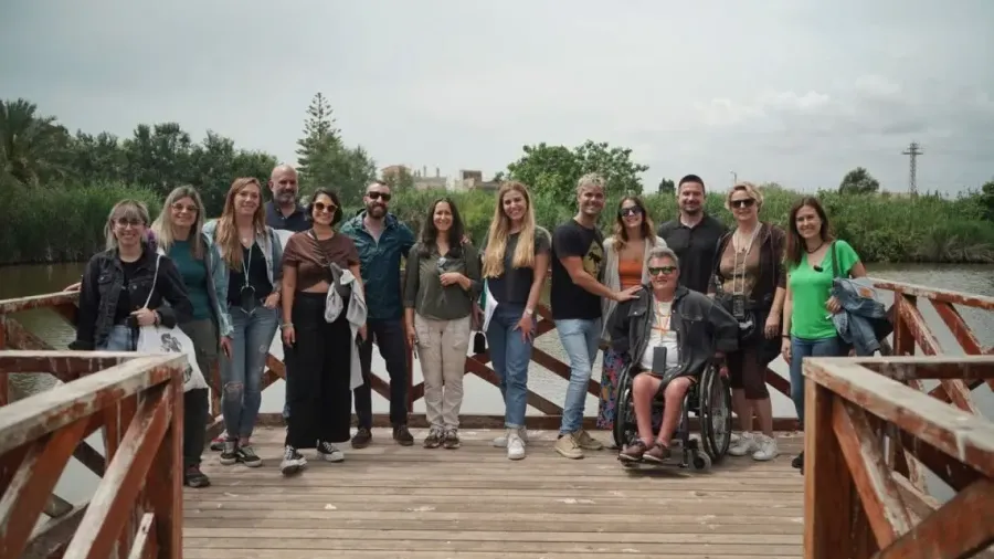 Grupo de personas posando en una pasarela de madera junto a una persona en silla de ruedas