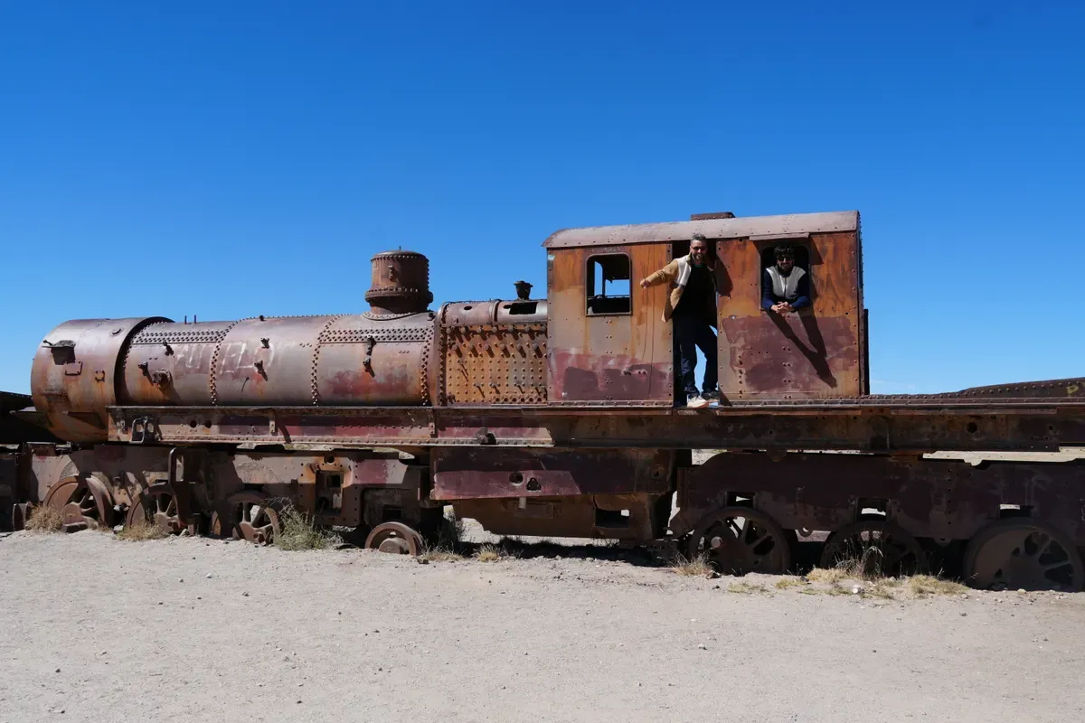 Antigua locomotora oxidada con gente subida en el cementerio de trenes de Uyuni