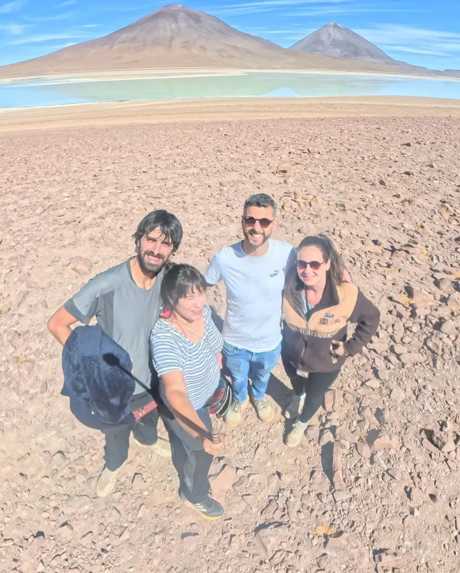 Los cuatro viajeros posando delante de una laguna turquesa con dos volcanes al fondo