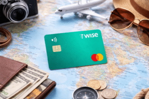 Tarjeta Wise sobre mapa del mundo con dinero, cámara y accesorios de viaje