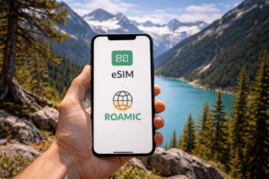 Persona usando un móvil con eSIM mientras viaja con vistas a un lago de montaña